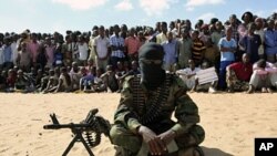 A member of Somalia's al-Shabab militant group sits during a public demonstration to announce integration with al Qaeda, Elasha, south of Mogadishu, February 13, 2012