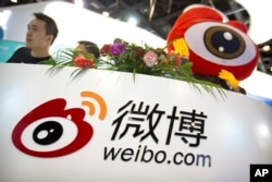 FILE - Staff members wait for visitors at a booth for Chinese microblogging website Sina Weibo at the Global Mobile Internet Conference in Beijing, April 27, 2017.
