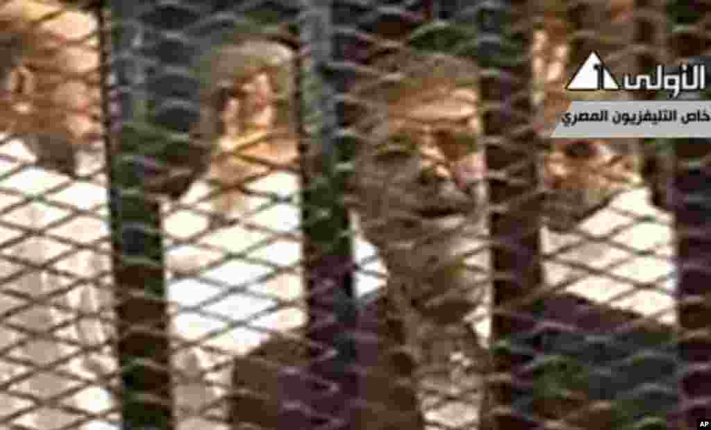 This image made from video broadcast on Egyptian State Television shows ousted President Mohammed Morsi speaking from inside a mesh cage as he stands with other defendants during a court hearing at a police academy compound in Cairo, Egypt, Monday, Nov. 4