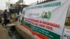 A security officer passes a banner put up in Lagos by Nigeria's Independent National Electoral Commission. It invites residents to test their voter cards before the general election March 28, 2015. 