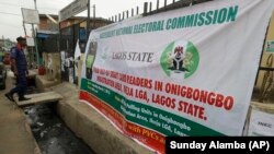 A security officer passes a banner put up in Lagos by Nigeria's Independent National Electoral Commission. It invites residents to test their voter cards before the general election March 28, 2015. 