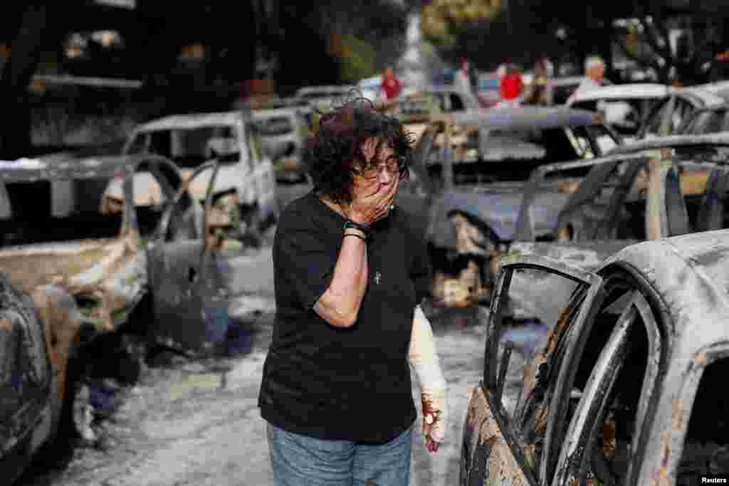 A woman reacts as she tries to find her dog, following a wildfire at the village of Mati, near Athens, Greece.