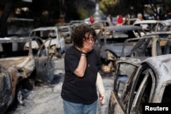 A woman reacts as she tries to find her dog, following a wildfire at the village of Mati, near Athens, Greece.