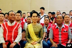 FILE - Myanmar's Foreign Minister Aung San Suu Kyi, center, sits with members of the United Wa State Army (UWSA) as they pose for photographs after a meeting of armed ethnic groups at a hotel in Naypyitaw, Myanmar, July 29, 2016.