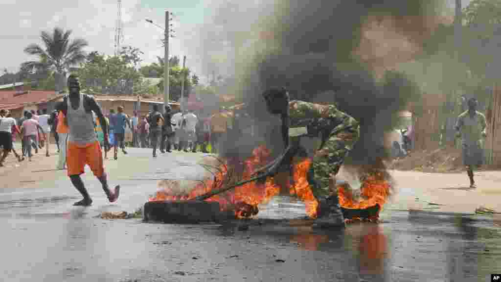 Un soldat de l&#39;armée burundaise tente d&#39;éteindre le feu d&#39;un pneu brulé par les manifestants &nbsp;dans la capitale Bujumbura, Burundi, lundi 27 avril 2015.