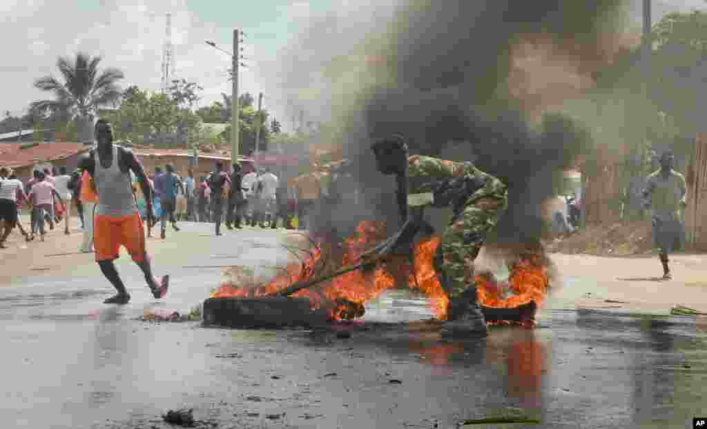 Un soldat de l&#39;armée burundaise tente d&#39;éteindre le feu d&#39;un pneu brulé par les manifestants&nbsp; dans la capitale Bujumbura, Burundi, lundi 27 avril 2015.