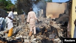 Residents watch as two men walk amidst rubble after Boko Haram militants raided the town of Benisheik, west of Borno State capital Maiduguri, Sept. 19, 2013.