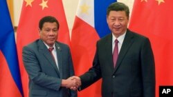 FILE - Philippine President Rodrigo Duterte, left, and Chinese President Xi Jinping pose for photographers on the sidelines of the Belt and Road Forum for International Cooperation at the Great Hall of the People in Beijing, May 15, 2017. 