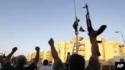 Libyan rebels gesture as they change the flag in Abu Salim district in Tripoli, Libya, August 25, 2011