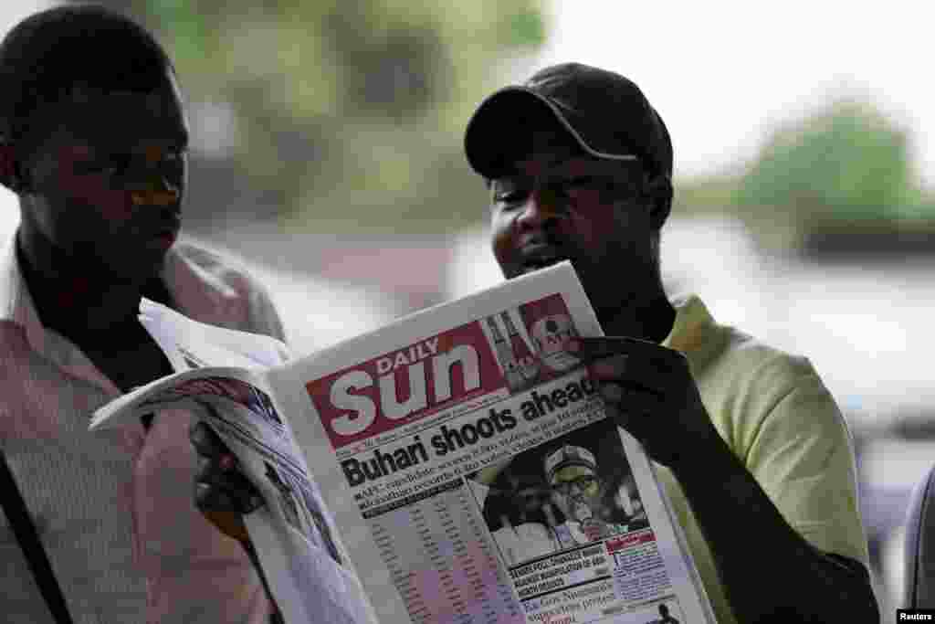 Seorang pria membaca surat kabar dengan berita utama mengenai pemilu, di Port Harcourt (31/3).&nbsp;​(Reuters/Afolabi Sotunde)