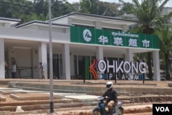 FILE - A man drives passed a Chinese supermarket located nearby the border of Thailand, in Koh Kong province, on April 3, 2019 (Sun Narin/VOA Khmer)