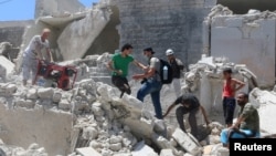 People walk on the rubble of a site hit by a barrel bomb in the rebel-held area of Old Aleppo, Syria, July 11, 2016. 
