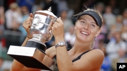 Petenis Rusia, Maria Sharapova memegang trophy juara Perancis Terbuka setelah mengalahkan petenis Italia, Sara Errani, Sabtu (9/6).