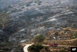 A fire engine drives past a burned area from a wildfire in the Sunland-Tujunga section of Los Angeles, Sept. 4, 2017.