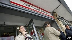 Unemployed factory worker Alejandro Jimenez, 35, left, smokes as he waits outside a government employment office for his turn to be attended in Madrid, 04 Jan, 2011