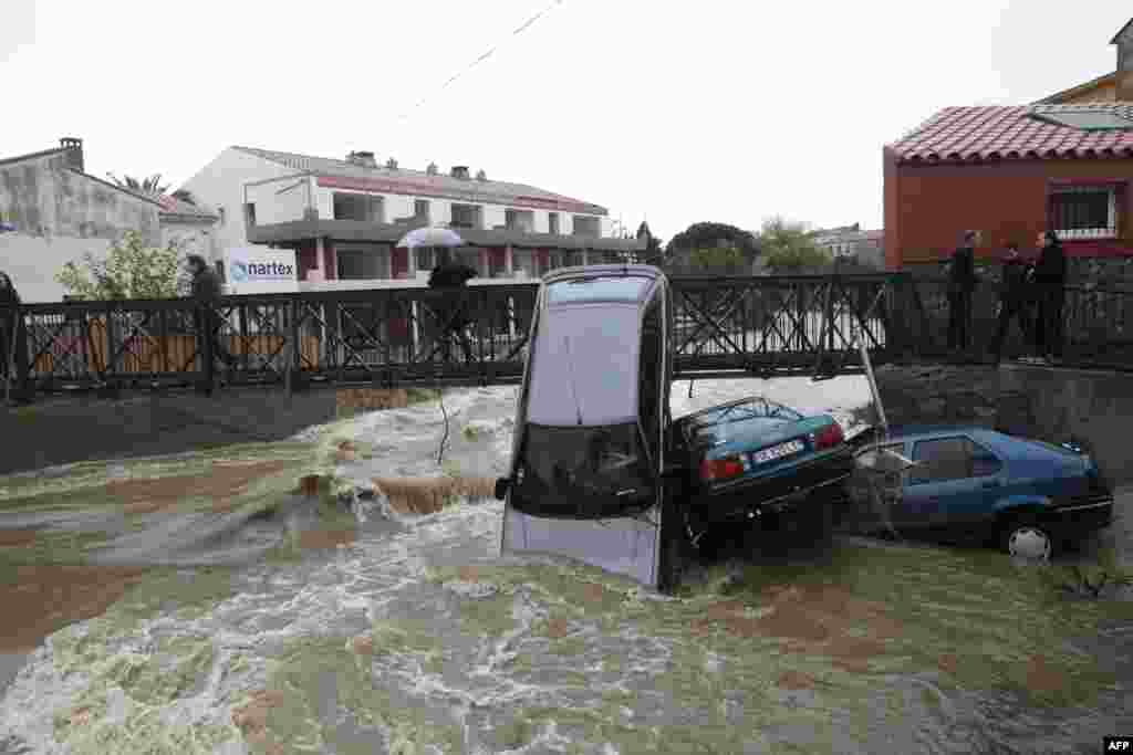 People walk on a bridge near damaged cars after the river Massane flooded the city of Argeles-sur-Mer in southern France, due to heavy rains.