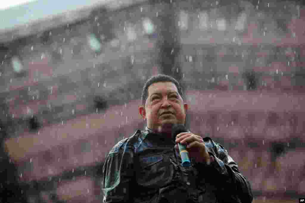 Under pouring rain, Venezuela's President Hugo Chavez holds a microphone during his closing campaign rally in Caracas, Venezuela, Thursday, October 4, 2012. 