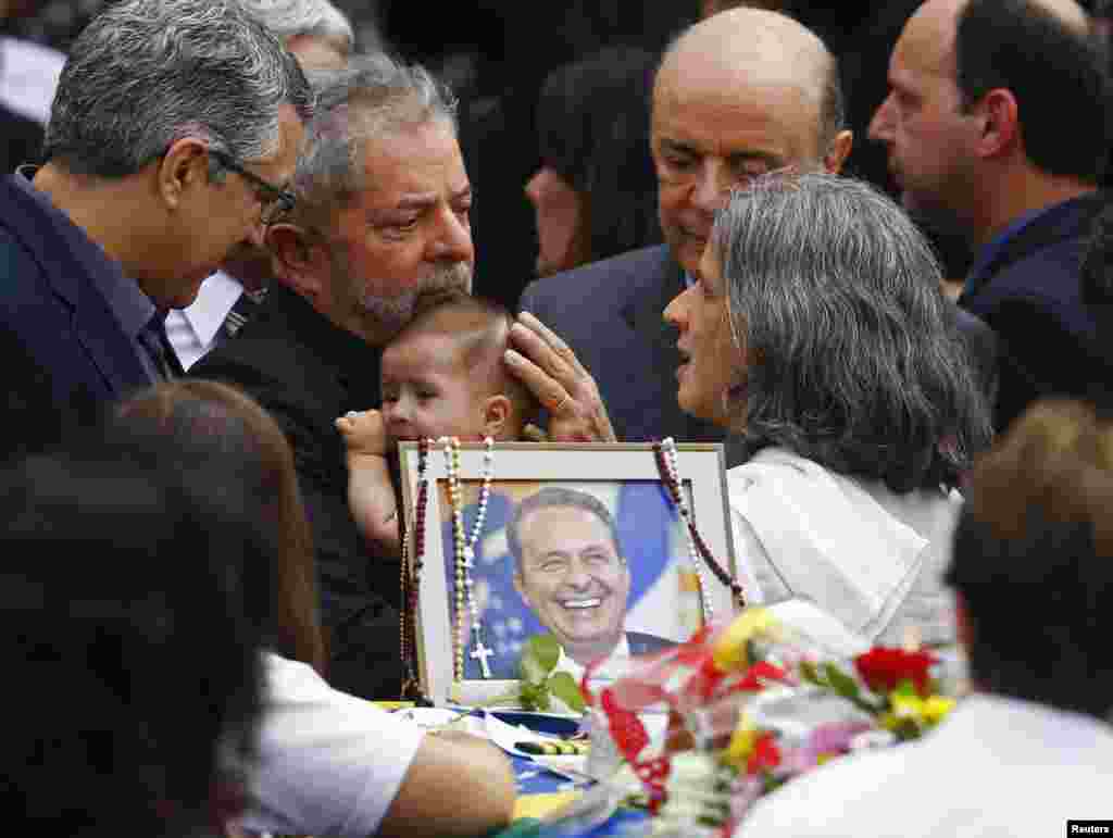 Brazil&#39;s former President Luiz Inacio Lula da Silva (2nd L) holds the infant son of late presidential candidate Eduardo Campos as he talks with Campos&#39; widow Renata, during the wake inside the Pernambuco Government Palace in Recife. The Brazilian Socialist Party leader, 49, was killed in a plane crash on Aug. 13.