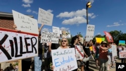 Protestors gather outside Dr. Walter James Palmer's dental office in Bloomington, Minn., Wednesday, July 29, 2015. Palmer reportedly paid $50,000 to track and kill Cecil, a black-maned lion, just outside Hwange National Park in Zimbabwe. (AP Photo/Ann Heisenfelt)