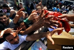 FILE - Syrian refugees and other migrants struggle to get dry food during aid distribution by municipality workers on the Greek island of Kos, Aug. 14, 2015.