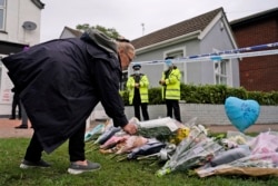 A woman places a floral tribute on the road leading to the Belfairs Methodist Church in Eastwood Road North, in Leigh-on-Sea, Essex, England, Oct. 16, 2021, site of the fatal stabbing Friday of member of parliament David Amess.