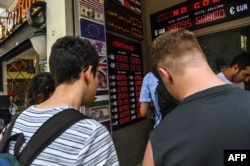 People change their money at a counter on the Istiklal avenue in Istanbul on Aug. 2, 2018 next to a panel indicating foreign exchange and Turkish lira rates.