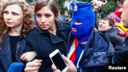 FILE - Russian punk band Pussy Riot members Maria Alyokhina (L) and Nadezhda Tolokonnikova (2nd L), along with a masked member of the group, speak to journalists during the 2014 Sochi Winter Olympics, in Adler, Feb. 20, 2014.