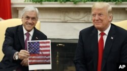 El presidente chileno Sebastián Piñera sostiene una imagen que muestra la bandera chilena al centro de la bandera estadounidense durante una reunión con el presidente Donald Trump en su oficina de la Casa Blanca.