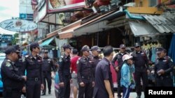 FILE - Bangkok city officials speak with a street vendor at the Khao San tourist street in Bangkok, Thailand, Aug. 1, 2018. 