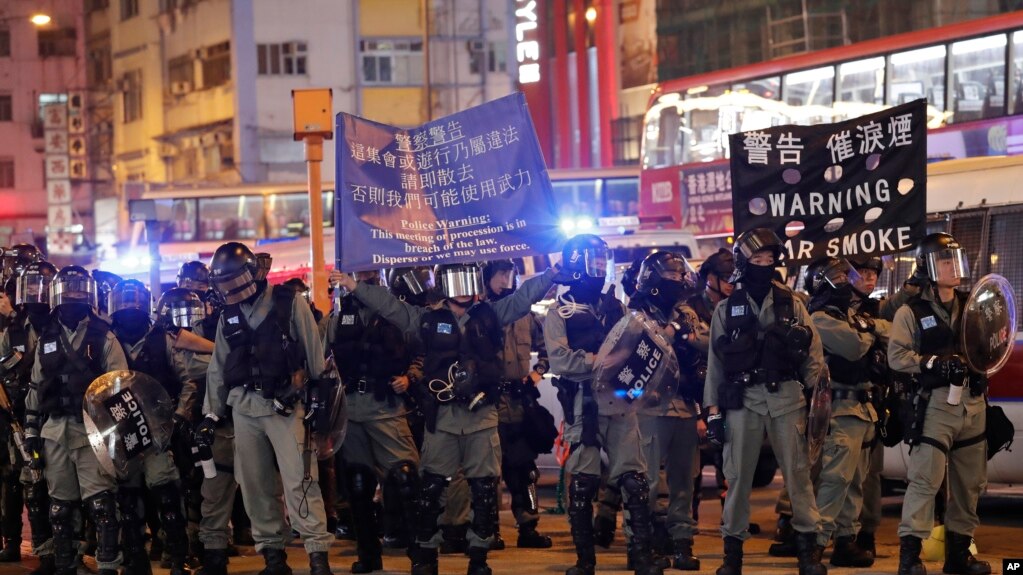 香港防暴警察在圣诞日向示威者展开警示将要采取镇压行动的旗子。(2019年12月25日)