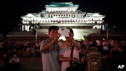 FILE - A North Korean couple use their smartphone to photograph fireworks in Pyongyang, July 27, 2014.