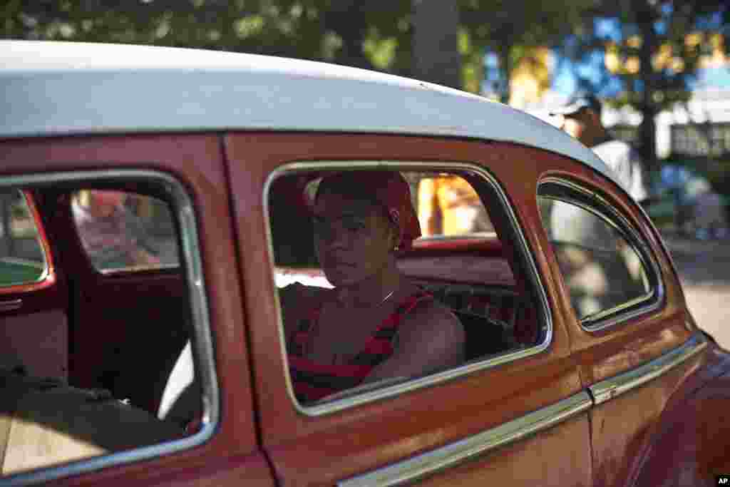 Seorang perempuan menunggu di dalam mobil klasik Amerika yang dulu digunakan sebagai angkutan umum di Havana, Kuba (18/12).&nbsp;(AP/Ramon Espinosa)