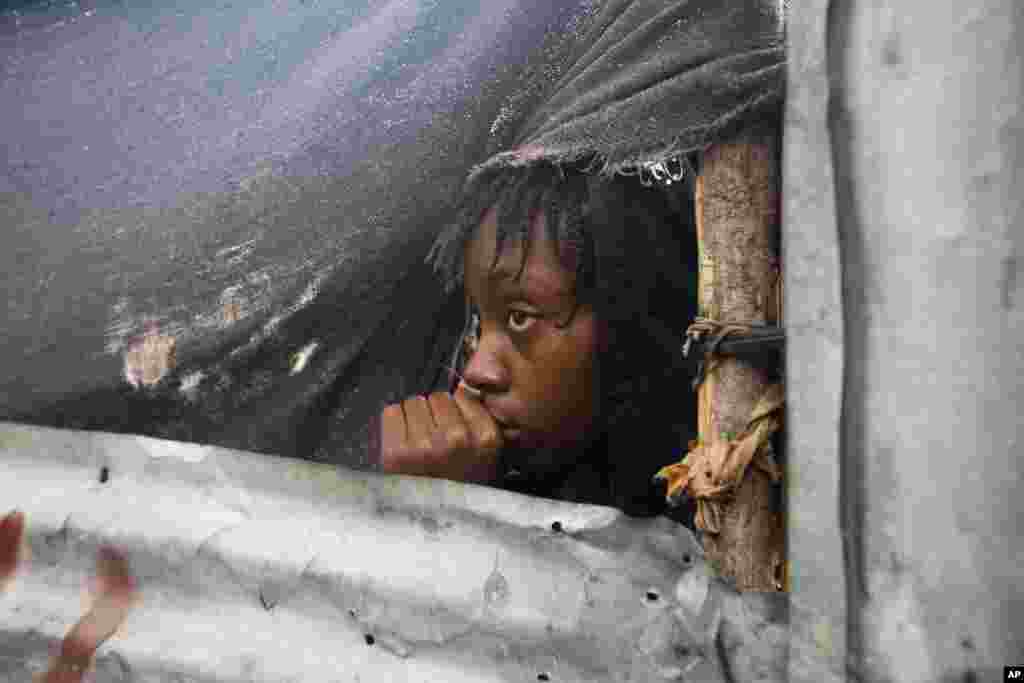 Seorang anak perempuan mengintip dari jendela rumahnya di Tabarre, Haiti, saat pihak berwenang tiba untuk mengevakuasi warga (3/10).&nbsp;(AP/Dieu Nalio Chery)