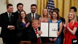 President Trump holds up an executive order that, among other things, requires colleges to certify that their policies support free speech as a condition of receiving federal research grants. (AP Photo, Jacquelyn Martin)