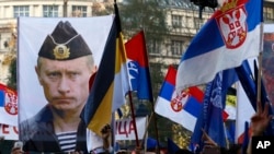 FILE - A supporter of Serbian ultranationalist leader Vojislav Seselj holds a picture of Russian President Vladimir Putin during a protest In Belgrade, Serbia. 