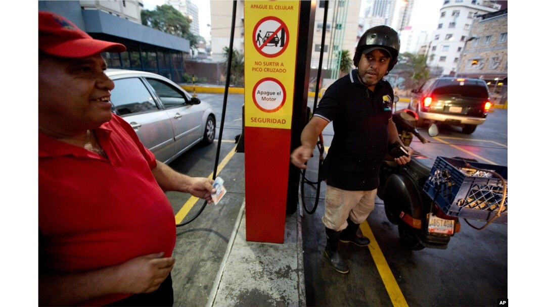 A motorcyclist pays about two Bolivars (3 cents of a dollar) after filling his scooter's tank at a gas station in Caracas, Venezuela, Feb. 17, 2016.