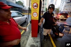 A motorcyclist pays about two Bolivars (3 cents of a dollar) after filling his scooter's tank at a gas station in Caracas, Venezuela, Feb. 17, 2016.