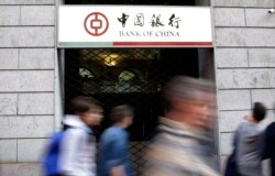 រូបឯកសារ៖ អ្នកធ្វើដំណើរដើរកាត់ផ្លាកសម្គាល់ធនាគារ Bank of China ស្ថិតក្នុងទីក្រុង Milan ប្រទេសអ៊ីតាលី កាលពីថ្ងៃទី១៥ ខែមេសា ឆ្នាំ២០១៥។