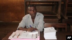 An election worker oversees the distribution of legislative election ballot papers at a polling station in Conakry, Guinea, Sept. 28, 2013.