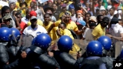 Students throw stones against riot police officers during their protest against university tuition hikes outside the union building in Pretoria, South Africa, Oct. 23, 2015.