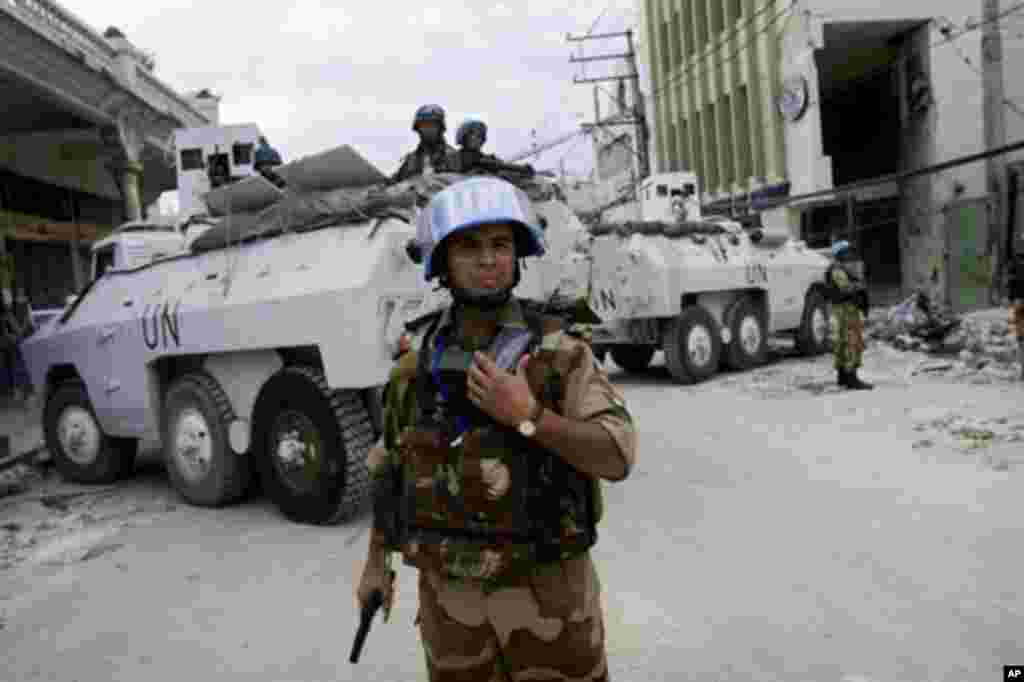 An officer from the Indian Formed Police Unit (FPU), working with Brazilian UN peacekeepers, helps to secure the perimeter of a bank in downtown Port-au-Prince, Haiti, 19 Jan 2010
