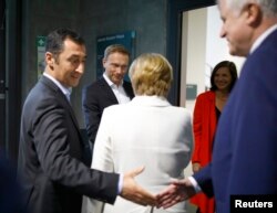 Leader of the German Green Party Cem Ozdemir, left, shake hands with Christian Social Union leader Horst Seehofer, right, while the leaders of the Christian Democratic Union, Angela Merkel, Free Democratic Party, Christian Lindner and Katrin Goering-Eckar