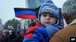 FILE - A man holds a child during celebration of the Flag Day at the Lenin's square, Donetsk eastern Ukraine.