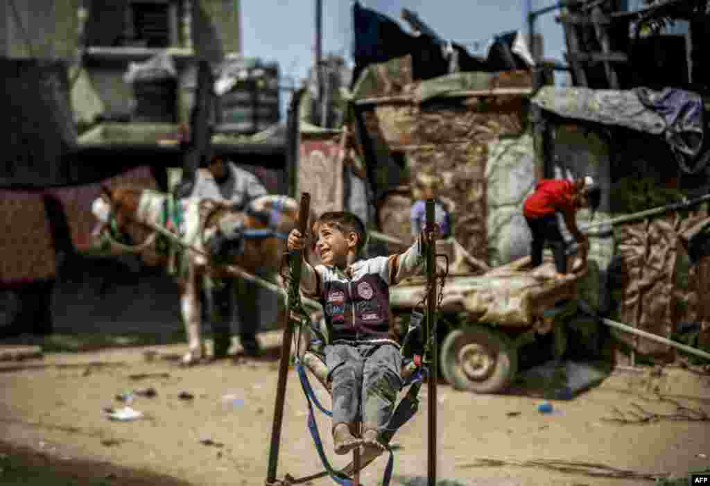 A Palestinian boy rides on a make-shift swing in an impoverished area in Beit Lahia in the northern Gaza Strip.