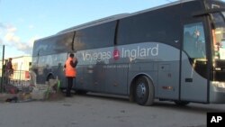 In this image taken from video, a bus carrying migrants leaves the migrant camp in Calais, France, Nov. 2, 2016.