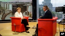 German Chancellor Angela Merkel (L) is seen prior to an interview at the studios of German public broadcaster ARD in Berlin, Germany, July 19, 2015.
