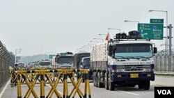 Truk-truk Korea Selatan mengangkut 300 ton terigu sebagai bantuan pangan untuk warga Korea Utara, sedang melewati perbatasan dua negara (26/7).