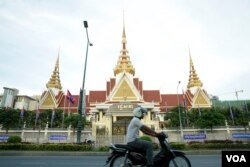 រូបឯកសារ៖ បុរស​ម្នាក់​បរ​ម៉ូតូ​កាត់​មុខ​រដ្ឋ​សភា​ក្នុង​ក្រុង​ភ្នំពេញ កាលពីល្ងាចថ្ងៃទី០២ ខែឧសភា ឆ្នាំ២០១៨។ (អូន ឆេងប៉រ/VOA)