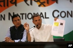 India's Congress party President Rahul Gandhi displays documents as he accuses Narendra Modi's government of buying 36 Rafale fighter jets from France's Dassault at a highly inflated price, in New Delhi, India, Oct. 11, 2018.