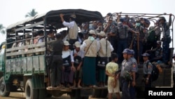 FILE - Volunteers and police board vehicles before proceeding to Rohingya refugee camps to collect data for the census in Sittwe, March 31, 2014.
